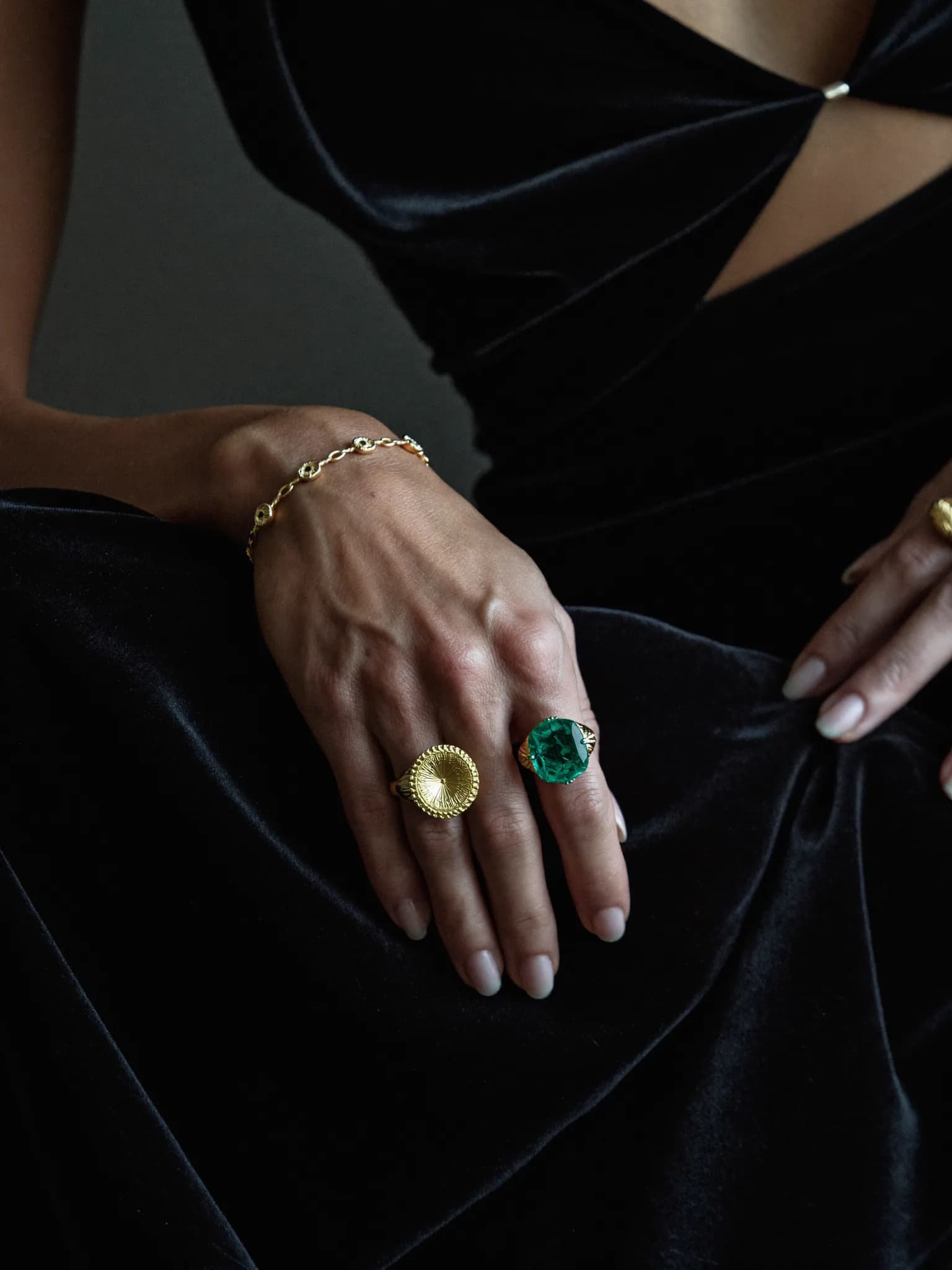 Gold watch, rings and a leather handbag arranged on warm stone