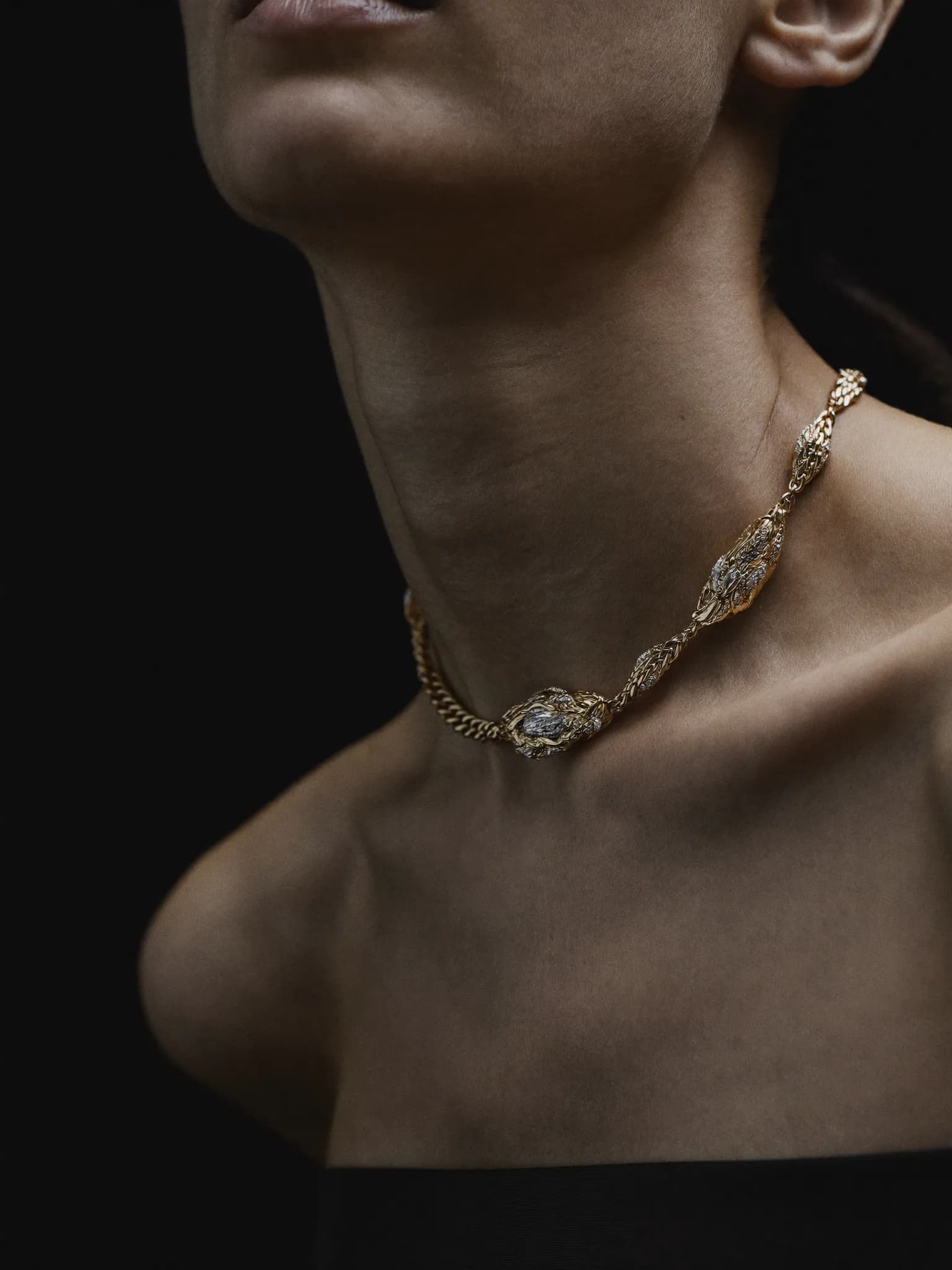 Sculptural gold chain necklace photographed in warm light