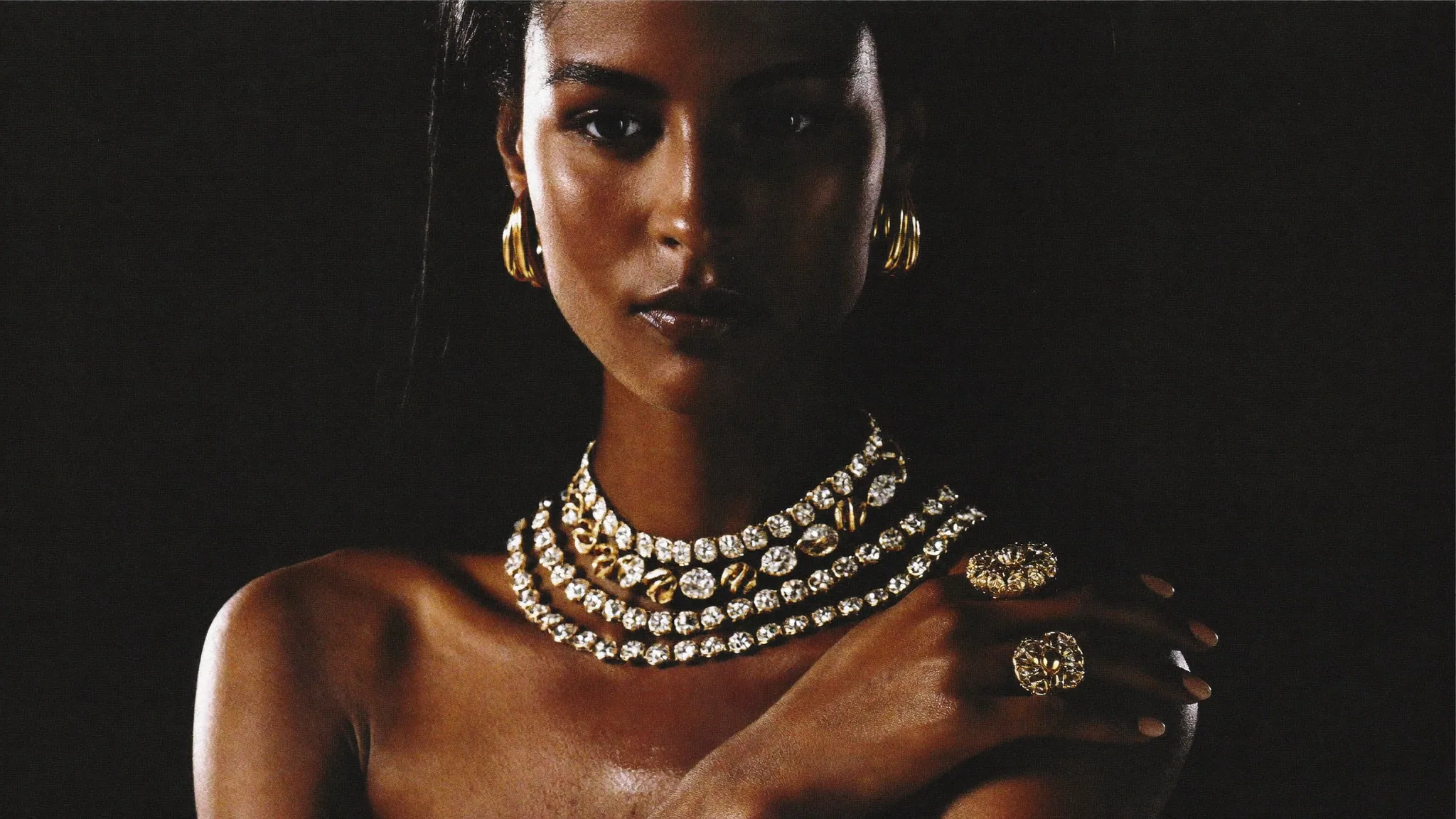 Model in amber silk wearing layered gold jewellery from the Wyns Collections atelier